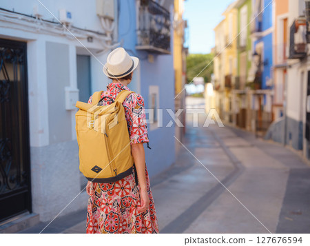 Tourism in Europe. Happy traveler girl visiting the colorful Spanish village with palm trees and beaches Villajoyosa, Alicante, Spain. back view 127676594