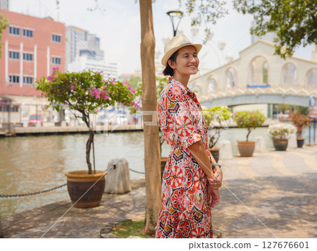 Young woman in ethnic dress and hat exploring the vibrant streets of Malacca, Malaysia. A blend of cultural heritage, colorful architecture, and tropical charm. Perfect travel and lifestyle moments. 127676601