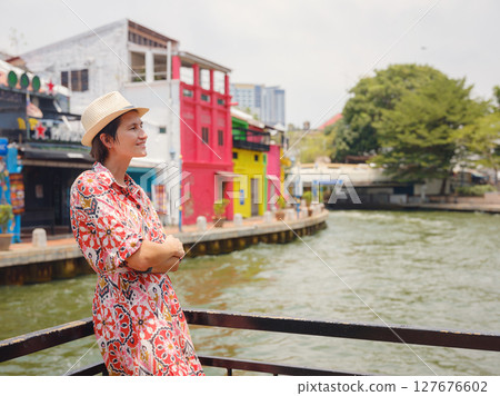 Young woman in ethnic dress and hat exploring the vibrant streets of Malacca, Malaysia. A blend of cultural heritage, colorful architecture, and tropical charm. Perfect travel and lifestyle moments. 127676602