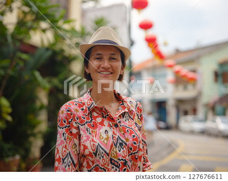 Young woman in ethnic dress and hat exploring the festive streets of George Town, Malaysia, during Chinese New Year. Vibrant lanterns, cultural celebrations, and historic charm create a unique 127676611