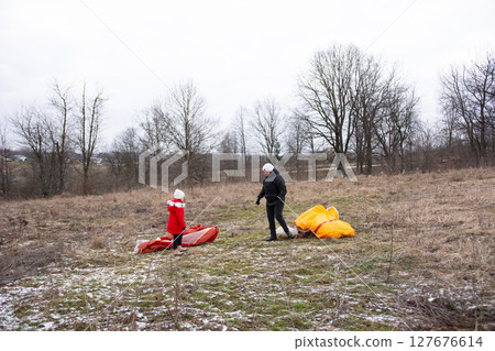 Family bonding while preparing colorful kites in a winter field, capturing the essence of outdoor fun and creativity 127676614