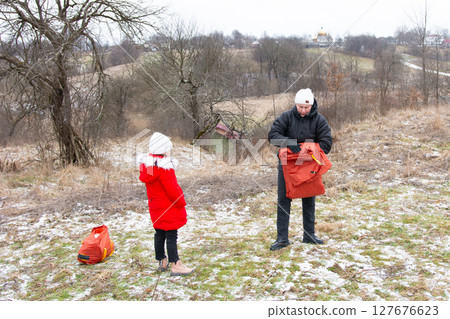 Bright winter adventure unfolds with a child and adult preparing gear in a snowy landscape surrounded by trees and distant hills Bright winter adventure unfolds with a child and adult preparing gear in a snowy landscape surrounded by trees and distant hills 127676623