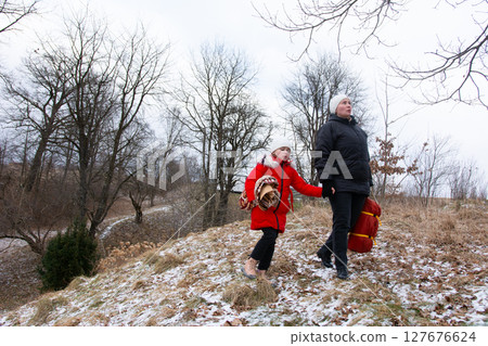 Winter walk with child in red coat exploring snowy landscape near trees during overcast weather in early afternoon Winter walk with child in red coat exploring snowy landscape near trees during overcast weather in early afternoon 127676624