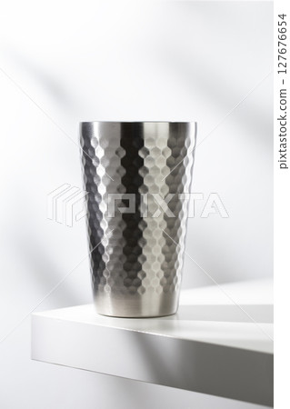 Stainless steel glass on a white table with clean, modern lighting. 127676654