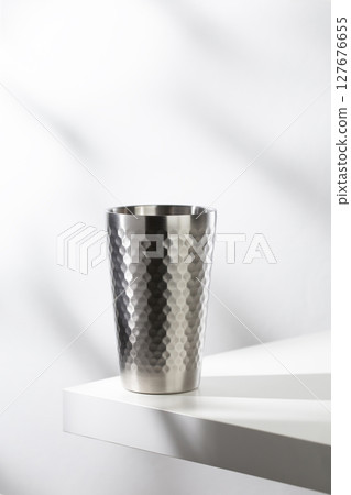 Stainless steel glass on a white table with clean, modern lighting. 127676655