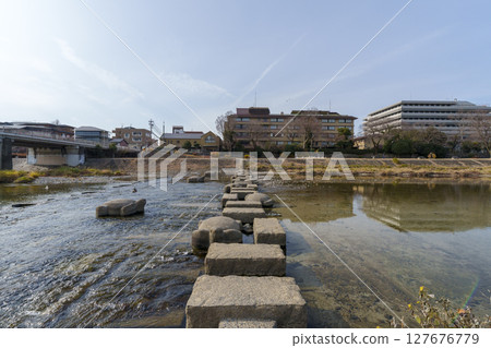 Stepping stones on the Kamo River and the townscape shining against the blue winter sky Stepping stones on the Kamo River and the townscape shining against the blue winter sky 127676779