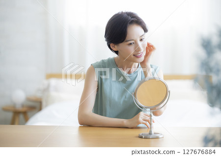 A woman in the bedroom doing skin care 127676884