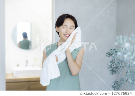一位女士洗臉並用毛巾擦乾 一位女士洗臉並用毛巾擦乾 127676924