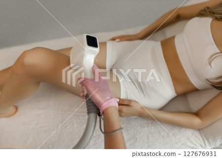Hair removal procedure. Cropped shot of young fit woman client receiving laser hair removal procedure on body in beauty clinic. Women beauty and cosmetology concept Hair removal procedure. Cropped shot of young fit woman client receiving laser hair removal procedure on body in beauty clinic. Women beauty and cosmetology concept 127676931