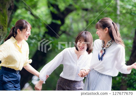A group of women walking side by side under the fresh greenery A group of women walking side by side under the fresh greenery 127677670