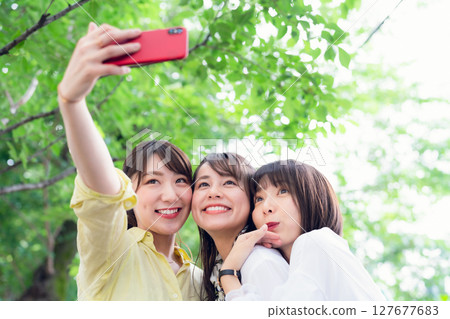 A group of women taking a selfie under the fresh greenery 127677683