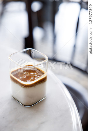 Cup of milk dirty coffee on white marble table by the window. 127677849