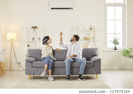 Married Couple Turning On Air Conditioner To Control Climate At Home 127678184