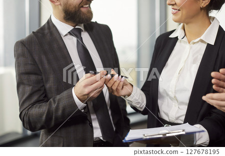 Cropped image of businessman giving pen to businesswoman for signing documents 127678195