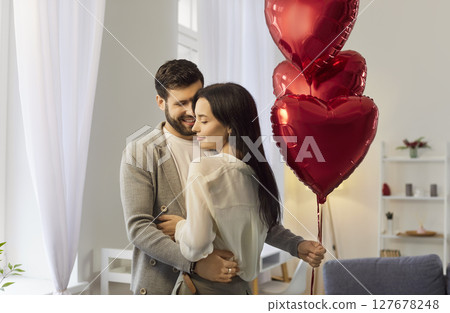 Couple Celebrates Valentine Day Embracing With Heart-Shaped Balloons 127678248