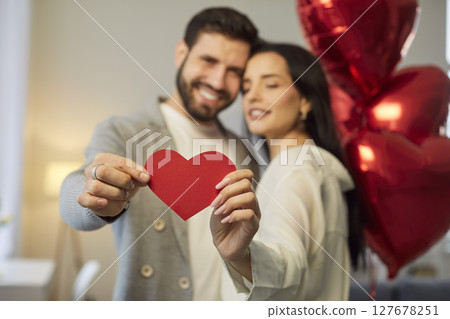 Young couple holding heart in hands and hugging celebrating holiday. Valentines day concept. Young couple holding heart in hands and hugging celebrating holiday. Valentines day concept. 127678251