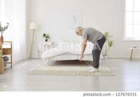 Senior man doing stretching sport exercises for health waking up early in the morning. Senior man doing stretching sport exercises for health waking up early in the morning. 127678331