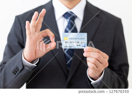 A businessman in a suit holding a credit card and making a circle sign A businessman in a suit holding a credit card and making a circle sign 127678350