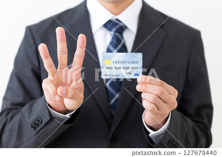 一位西裝革履的商人，手裡拿著信用卡，伸出三根手指 127678440