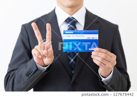 一位身著西裝的中年男性商人拿著銀行存摺做出和平手勢 127678442