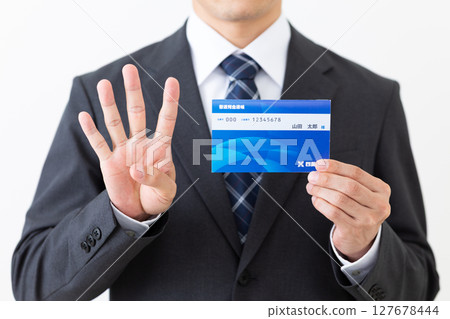 一位身穿西裝的中年男性商人，手裡拿著銀行存摺，舉起四根手指 127678444