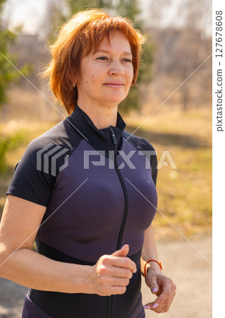 Woman running in a park as part of her morning fitness routine. Cardio activity, healthy lifestyle, and self-discipline outdoors. 127678608