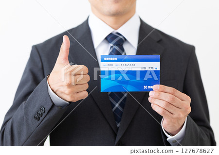 一位身著西裝的中年男性商人拿著銀行存摺豎起大拇指 127678627