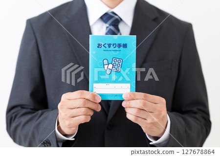Middle-aged male businessman wearing a suit holding a medicine notebook 127678864