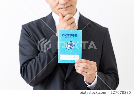 Middle-aged male businessman wearing a suit holding a medicine notebook 127678880
