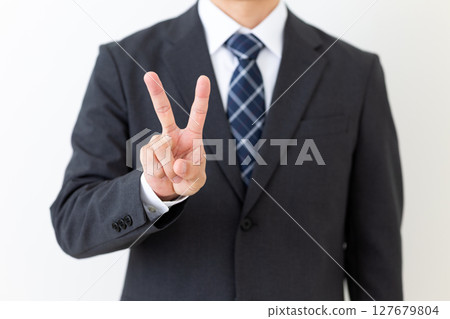 Middle-aged male businessman in a suit making a peace sign 127679804