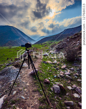 Camera mounted on tripod capturing serene landscape in mountains Camera mounted on tripod capturing serene landscape in mountains 127680113