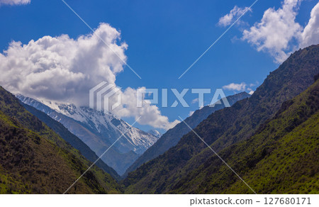 Majestic snow-capped mountains under serene clouds in Kyrgyzstan 127680171