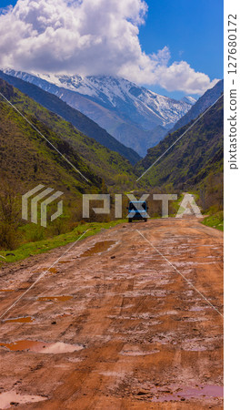 Van on muddy road with mountains in serene rural setting in Kyrgyzstan Van on muddy road with mountains in serene rural setting in Kyrgyzstan 127680172