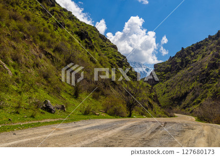 Serene road winding through peaceful mountainous landscape 127680173