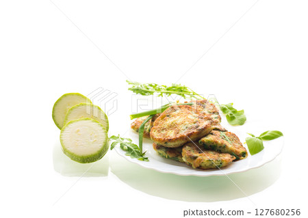 appetizing zucchini pancakes with green onions in a plate on a white background 127680256
