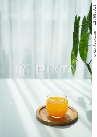 Orange juice on white table under sunshine 127680311