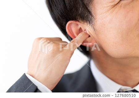 一位穿著西裝的中年男性商人用小指掏耳朵 127680510