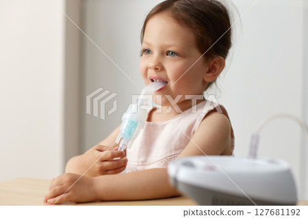 cute little toddler girl inhaling medicine on nebulizer and holding it on her own 127681192