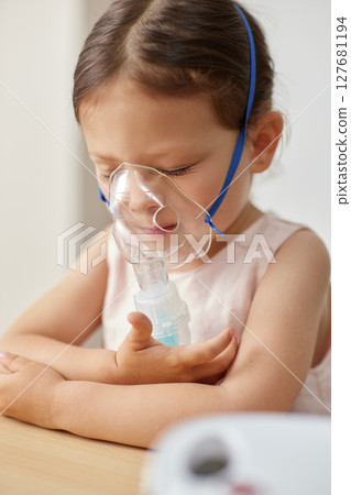 cute little toddler girl inhaling medicine on nebulizer and holding it on her own 127681194