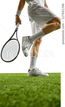 Tennis player in white sportswear holding racket on green grass court preparing to serve. Tennis player in white sportswear holding racket on green grass court preparing to serve. 127681390