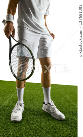 Tennis player in white attire holding racket standing on green grass court ready for match. Pre-match mindfulness 127681392