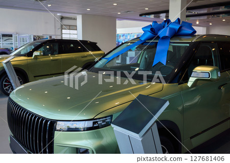 The new car is wrapped in a red bow. Beautiful gift concept. The new car is wrapped in a red bow. Beautiful gift concept. 127681406