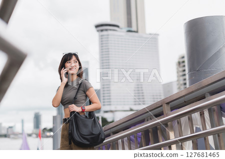 Solo southeast asian woman teenager blogger world travel tourism Bangkok Thailand express joy to friend smartphone. Wait for Chao Phraya river boat for local cultural experience. Asia explorer Solo southeast asian woman teenager blogger world travel tourism Bangkok Thailand express joy to friend smartphone. Wait for Chao Phraya river boat for local cultural experience. Asia explorer 127681465