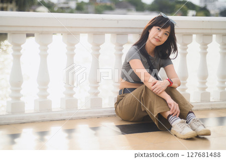 Happy young southeast asian woman teenager blogger on solo tourism for local cultural experience. World travel explorer in Bangkok Thailand near Chao Phraya river. Asia tourism concept Happy young southeast asian woman teenager blogger on solo tourism for local cultural experience. World travel explorer in Bangkok Thailand near Chao Phraya river. Asia tourism concept 127681488