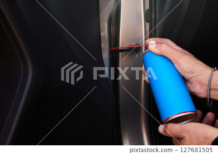 Applying spray lubricant to car door hinges helps keep them functioning smoothly 127681505