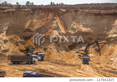The process of loading sand in a sand quarry. Trucks are waiting for cargo. The process of loading sand in a sand quarry. Trucks are waiting for cargo. 127681825
