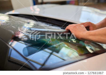 The Professional Windshield Tinting Process Conducted in a Modern Auto Showroom Environment 127681867