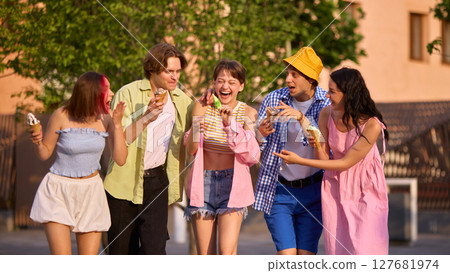 Group of friends enjoying ice cream and laughter outdoors on sunny summer day 127681974