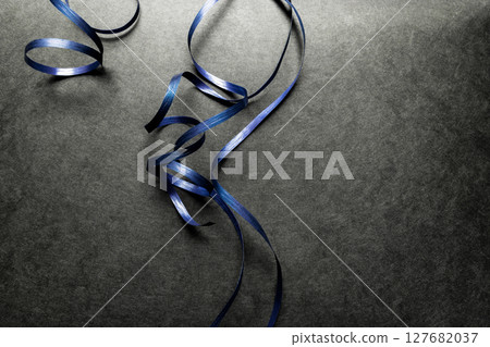 Blue Wrapping Ribbon on Black Surface Background 127682037