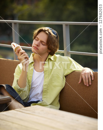 Chill style. Young man relaxing on outdoor patio with ice cream cone Chill style. Young man relaxing on outdoor patio with ice cream cone 127682053